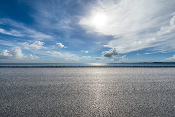 Empty asphalt road near the lake under blue sky
