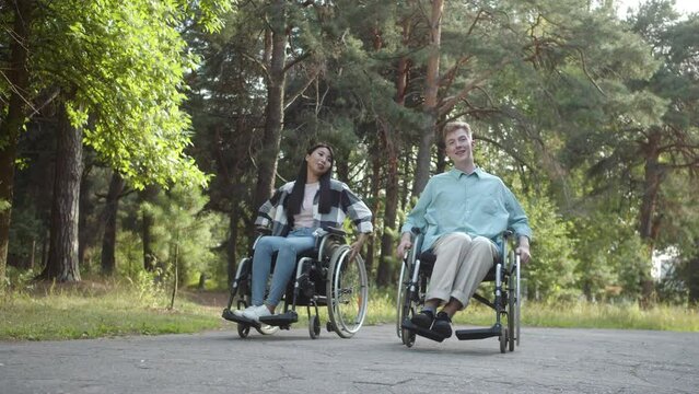 Two disabled young friends are walking in the forest and talking to each other, slow motion