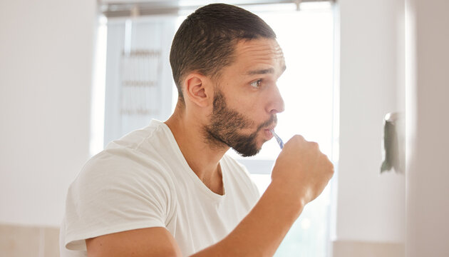 Twice a day keeps the cavities away. Shot of a young man brushing his teeth in the morning.