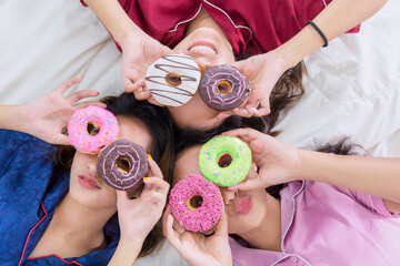 Top down view of girls covering eyes with donuts