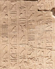 Ancient Egyptian hieroglyphs on the stone walls of the Karnak Temple in Luxor, Egypt