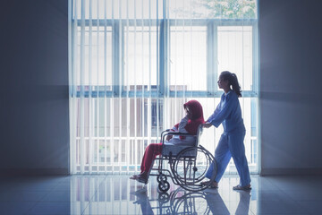 Female nurse push old Muslim woman on wheelchair