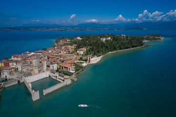 Aerial view on Sirmione sul Garda. Italy, Lombardy. Rocca Scaligera Castle in Sirmione. Boat with tourists near the main castle. View by Drone.