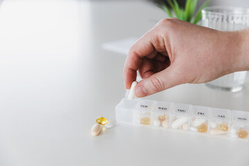 Closeup of female elderly hands sorting pills. Medical pill box with doses of tablets for daily...
