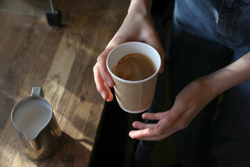 Barista prepares coffee in a paper cup