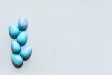 Blue lavender chocolate easter candy eggs on paper background.