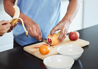 Summer is the best time for fruit. Shot of a couple peeling and cutting up fruit together.