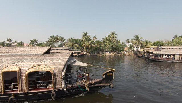 Wooden Boat sailing on the Alleppey waterway, local environment along Tropical river bank. India