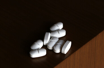 Fototapeta na wymiar Paracetamol or ibuprofen pills photographed at high magnification on the corner of a table
