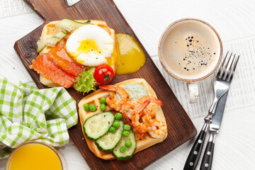 Breakfast waffles with fried eggs, salmon, cucumber and prawns