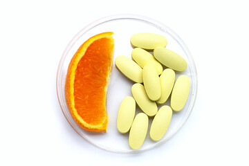 Vitamin c pills with orange fruit on white background.