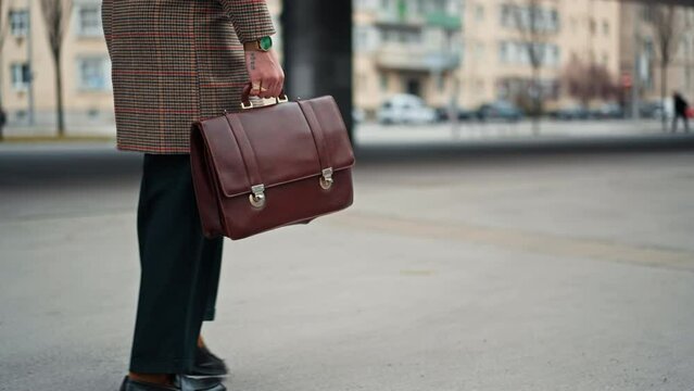 close up young Businessman going to work by walk. holding a leather bag in his hand. Commuting to the Office. Public transport