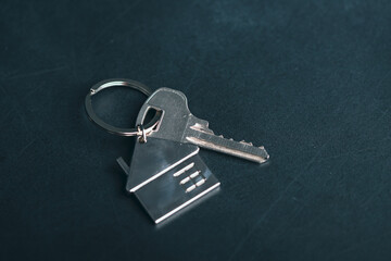 Key with silver house shaped pendant on dark background