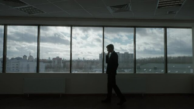 Contour lighting, businessman walks in front of a panoramic window, waiting process, morning in a modern office, natural lighting, the thinking process.