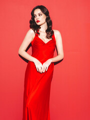 Beauty portrait of young brunette woman with evening makeup and perfect clean skin. Sexy model with curly hair posing in studio. With red bright natural lips. Isolated. In fashion  dress