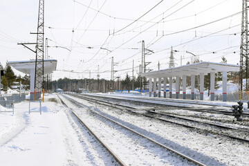 Fototapeta na wymiar Empty railway track and empty passenger platform, winter landscape.
