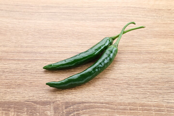 Green chili served in bamboo plate on wooden table.
