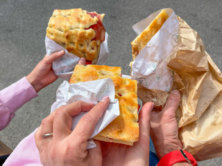 Eating focaccia with bresaola, multiple hands holding food.