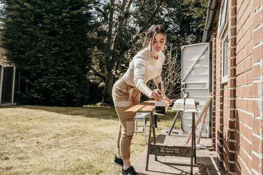 Young Woman Painting Cladding In The Garden, DIY Project