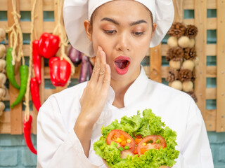 Asian woman in chef's uniform is cooking in the kitchen.