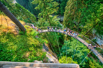 Naklejka premium Vancouver, Canada - August 11, 2017: People at Capilano Bridge. It is a Suspension bridge crossing the Capilano River, 140 metres long and 70 metres above the river.