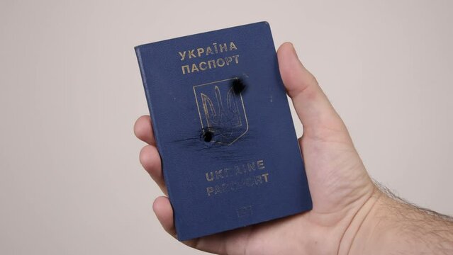 War between Russia and Ukraine. The concept of murder, occupation, aggression. Male hand holds a blue passport of Ukraine.