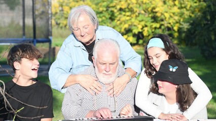 Man explaining how to use electrical piano outdoor to his grandchildren