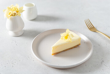 Piece of Classic New York Cheesecake with vanilla flower on white Concrete Background, side View, close up. Confectionery menu, sweet dessert recipe