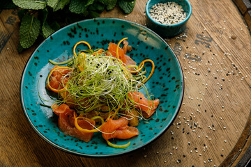 Thai food, salad with salmon in a plate on a wooden table
