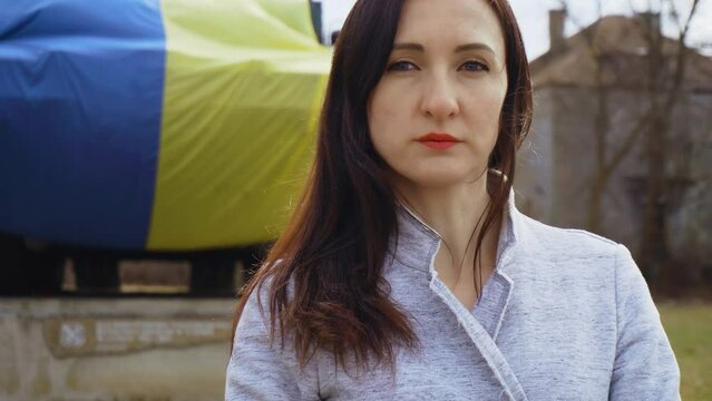 Portrait ukrainian woman standing in front of national flag during state invasion and fighting for freedom and independence. Concept of partnerships and allied countries and nations