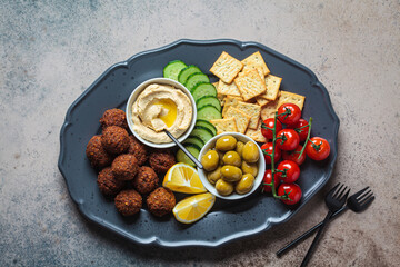 Falafel platter with hummus, olives, crackers and vegetables. Healthy vegan food concept.