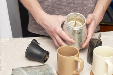 Fototapeta na wymiar a man makes coffee in a geyser sets a strainer for ground coffee in a geyser