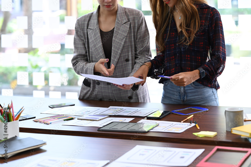 Poster two young female designer brainstorming and discussing for mobile application software design projec
