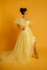 Profile portrait of a beautiful middle-aged woman in a yellow dress, her hair pulled up against a yellow background