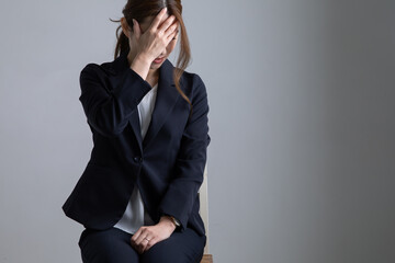 頭を抱えるスーツの女性　Dismissal