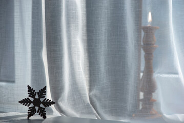 Candle light in the interior.Composition of objects on the windowsill.Delicate tulle on the windowsill and holiday items.