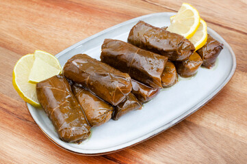 Dolmades on light plate with lemon slices in studio lit shot with ample copy space