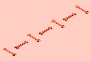 Three dimensional render of row of orange colored wrenches flat laid against beige background