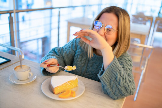 Happy Young Woman Enjoying Lemon Cake At Table