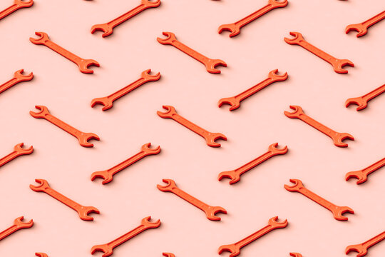 Three dimensional pattern of rows of orange colored wrenches flat laid against beige background