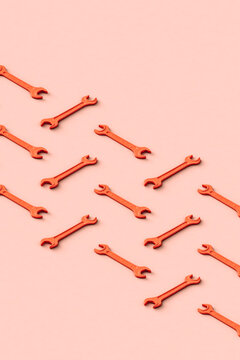Three dimensional render of rows of orange colored wrenches flat laid against beige background