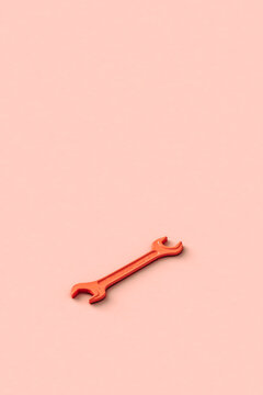 Three dimensional render of orange colored wrench lying against beige background