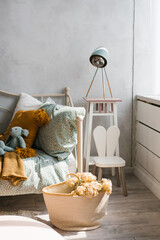 Stylish children's room of the child. Wicker basket with flowers, pillows on the bed mint and brown