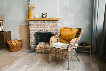 A wicker armchair with a yellow cushion near a brick fireplace with firewood, a children's wooden toy wheelchair in the Scandinavian-style living room