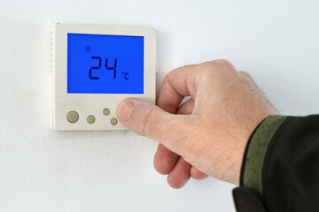 Male hand using of home heating and cooling system control unit