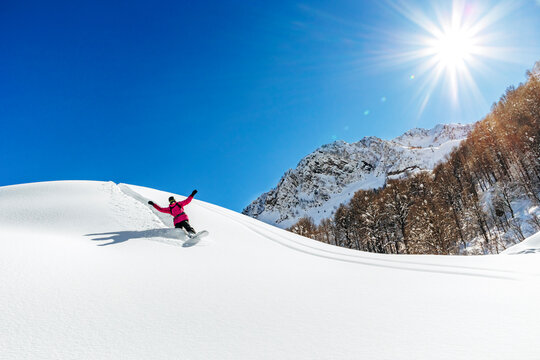Man snowboarding on snowy mountain on sunny day