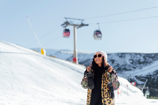 Smiling woman holding winter gloves enjoying at ski resort