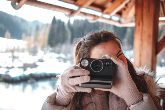 Young woman photographing with retro instant film camera for vintage style picture.