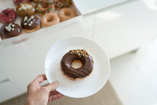 Hand of woman holding plate of doughnut
