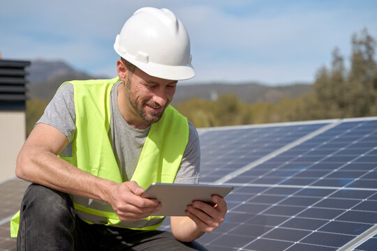 Smiling engineer using tablet PC by solar panels on sunny day